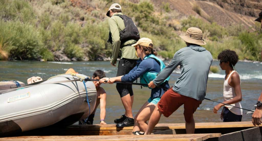 a group of outward bound students haul a raft out of the water onto a trailer